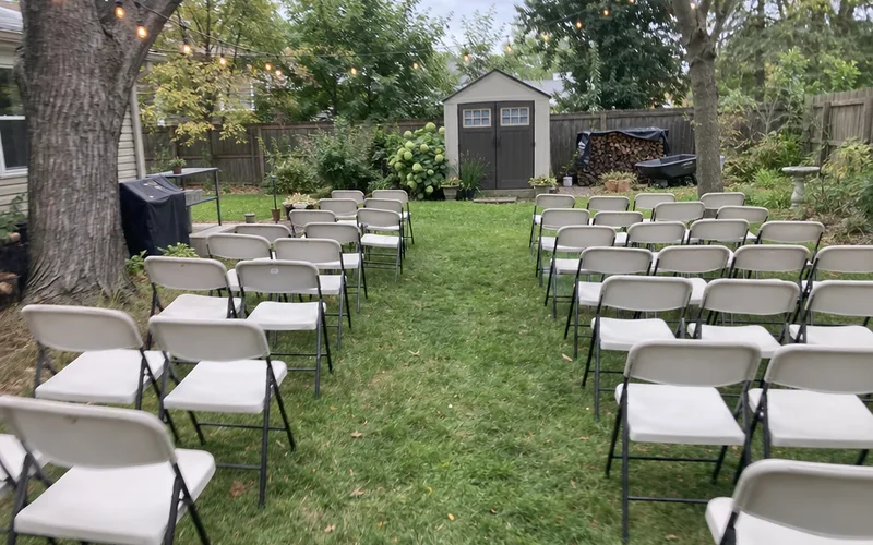 Rented folding chairs set in rows with an aisle on a family backyard lawn