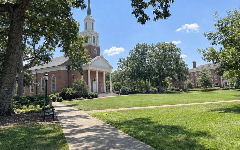 Brick college chapel beside an empty green quad in summer