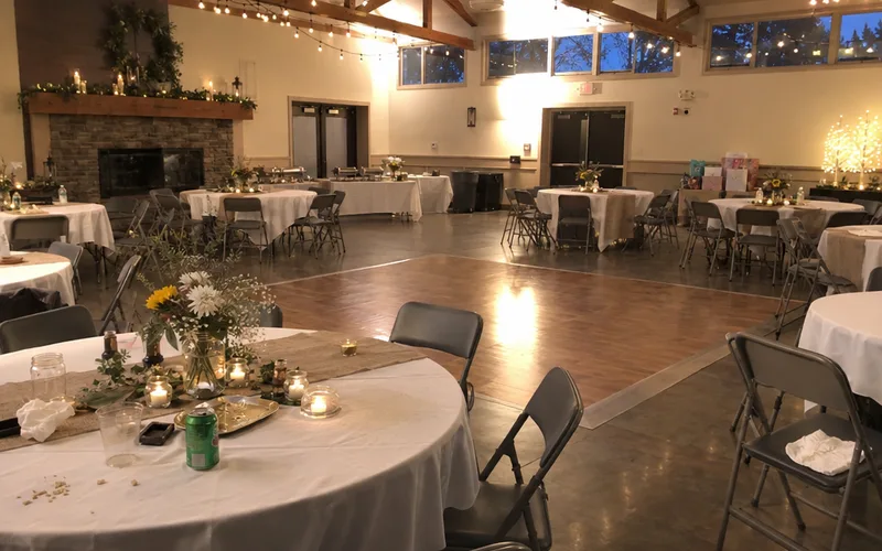 Community center hall with round tables and string lights set for a party